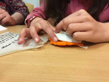 Un élève attache son sceau réalisé avec de la pâte à modeler avec une queue en parchemin.