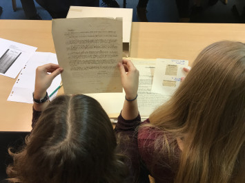 Deux jeunes filles en salle de classe étudient des documents des Archives du Calvados