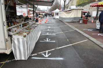 Sur la photographie, on voit qu'une signalétique a été peinte sur le sol afin de respecter la distanciation physique au niveau de l'étalage des commerçants du marché.