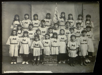 Un groupe de petites filles en tunique blanche, avec un logo représentant un lion utilisé comme emblème par l'Avant-Garde Caennais
