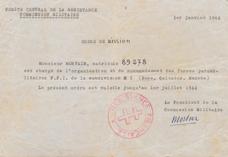 Il est écrit : "Ordre de mission. Monsieur Morvain, matricule 89278 est chargé de l'organisation et du commandement des forces paramilitaires F.F.I de la subdivision M1 (Eure, Calvados, Manche). Le présent ordre est valable jusqu'au 1er juillet 1944. Le Président de la Commission Militaire Mortier". Un tampon résistance française avec la croix de lorraine est apposé.