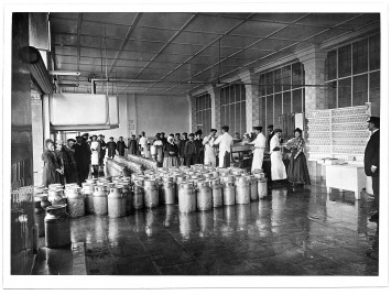 Les bidons de lait jonchent le sol à côté du personnel de l'usine réuni en nombre.