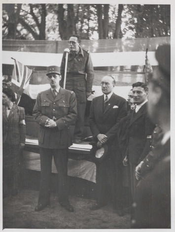 Au premier plan, on peut observer le général de Gaulle et François Coulet, à sa gauche, entourés de quelques Bayeusains. Au second plan, se trouve une estrade, sur laquelle Maurice Schuman s'exprime devant un micro.