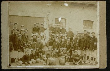 Photographie de groupe, des membres du club posent avec un drapeau et des instruments de musique.
