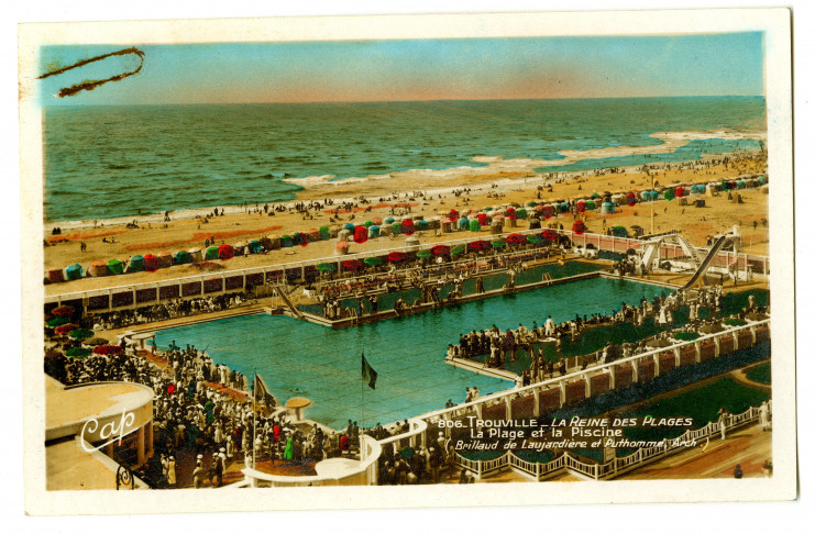 La piscine olympique de Trouville est attenante à la plage. On voit ainsi le bassin au premier plan et au second plan la mer. Une foule compacte entoure la piscine.