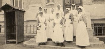 9 infirmières vêtues de blanc posent pour la photographie.