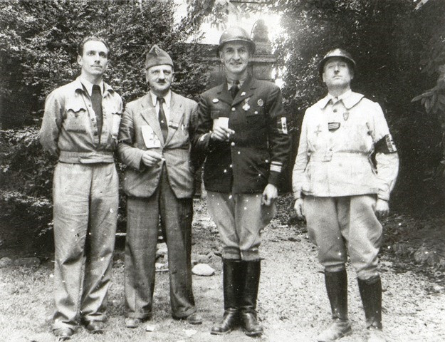 Les quatres hommes sont dans diverses tenues militaires. Léonard Gille est reconnaissable à son casque, son brassard FFI à la Croix de Lorraine et sa grande taille. Il porte ici des bottes et lève un verre de la main droite.